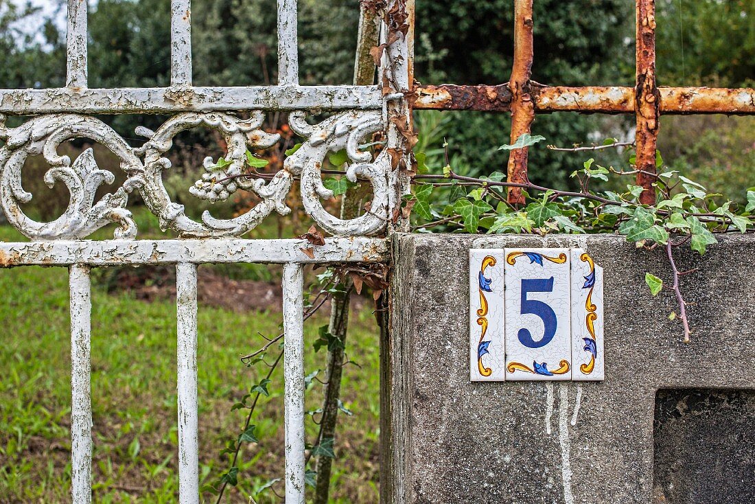 Rusty, weathered metal fence & wall with house number