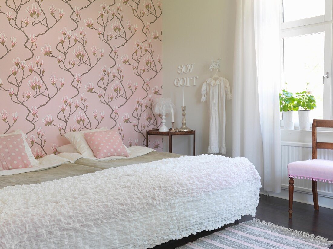 Einzelbetten nebeneinander gestellt mit weisser Tagesdecke, an Wand rosa Tapete mit Magnolienmotiven in romantischem Schlafzimmer