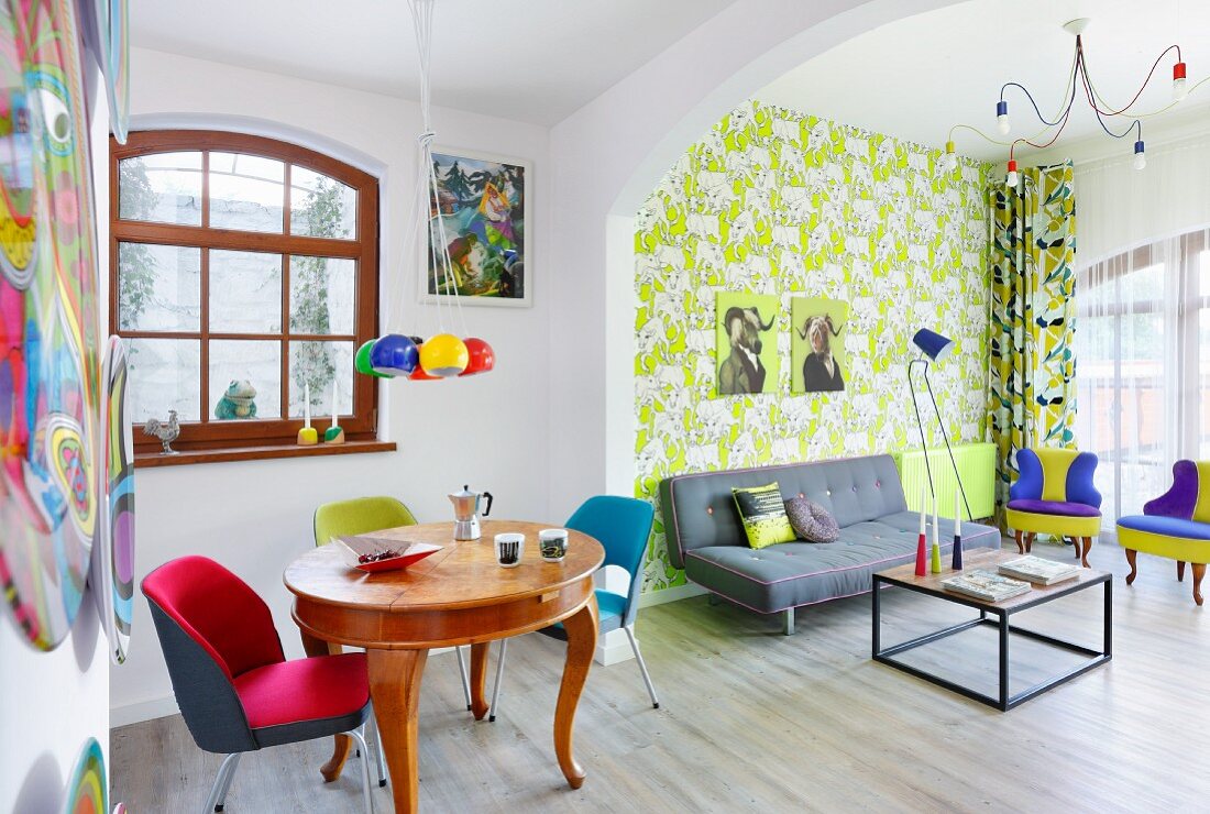 Farbenfroher Wohnbereich mit Mustertapete im Retro-Ambiente und antikem Esstisch