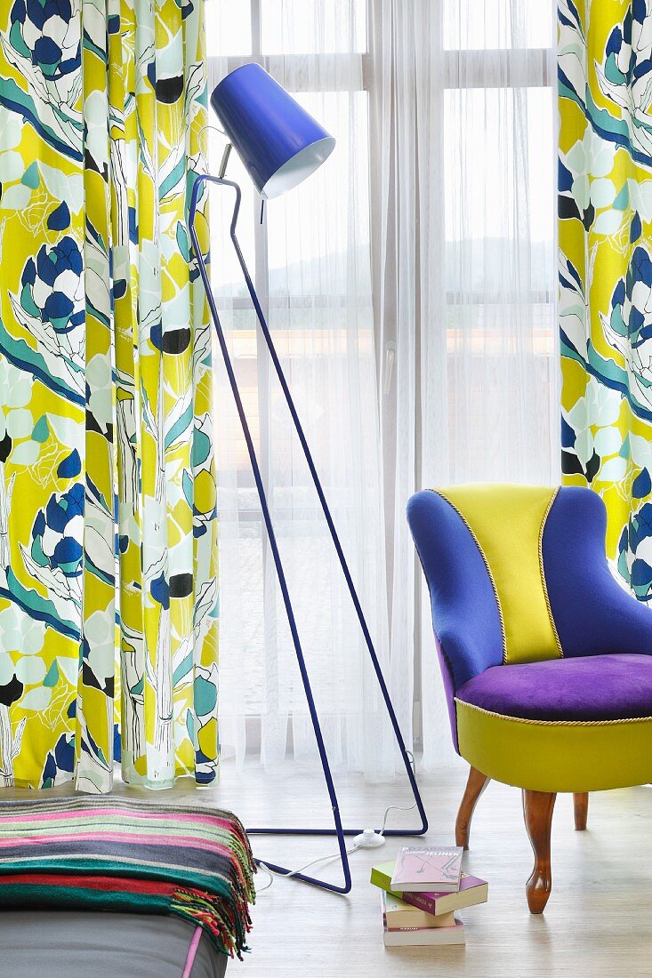 Colourful reading corner with retro standard lamp, multi-coloured easy chair and patterned curtains