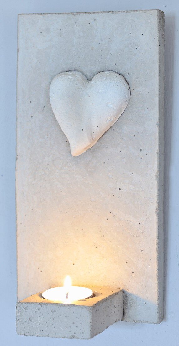 Concrete candle sconce with heart motif and lit tealight