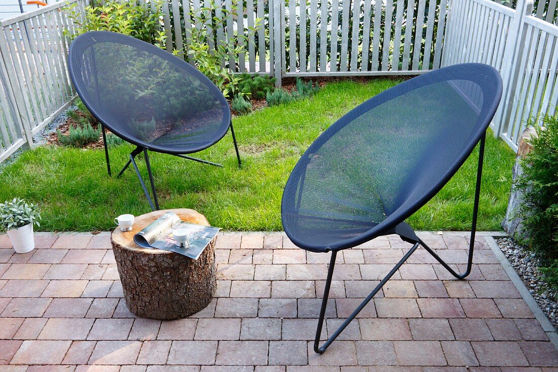 Moderne Outdoor Sessel mit grauem, netzartigem Bezug in kleinem, eingezäuntem Garten
