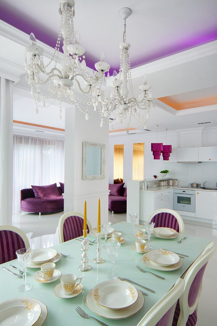 Elegant gedeckter Esstisch in neobarockem Essbereich mit Kristallkronleuchtern und violetten Farbakzenten