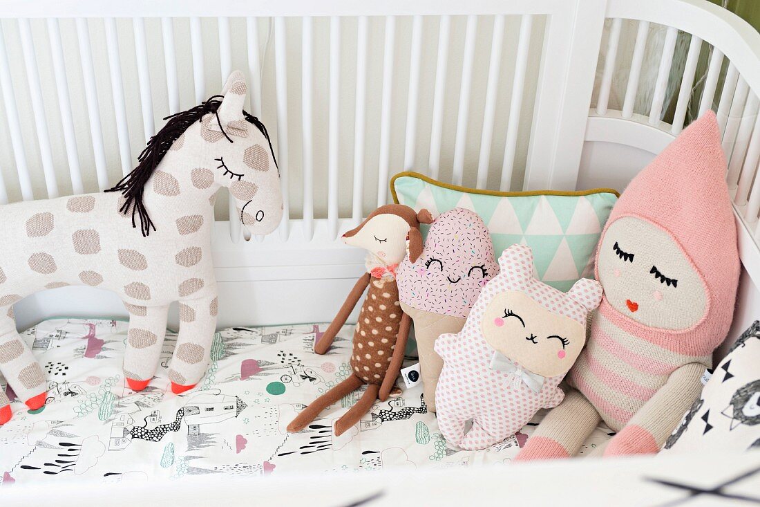 Fabric soft toys with closed, sleeping eyes in cot