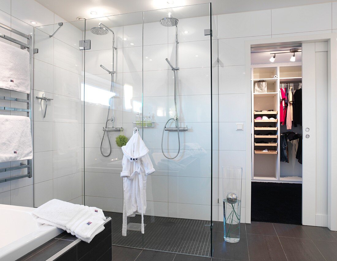 Floor-level double shower with glass screen in minimalist bathroom with sliding door leading to dressing room