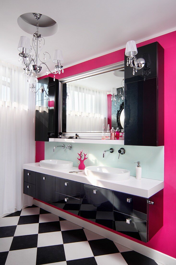 Schwarzer Waschtisch mit zwei Becken, darüber schwarze Hängeschränke und Spiegel an pinkfarbener Wand