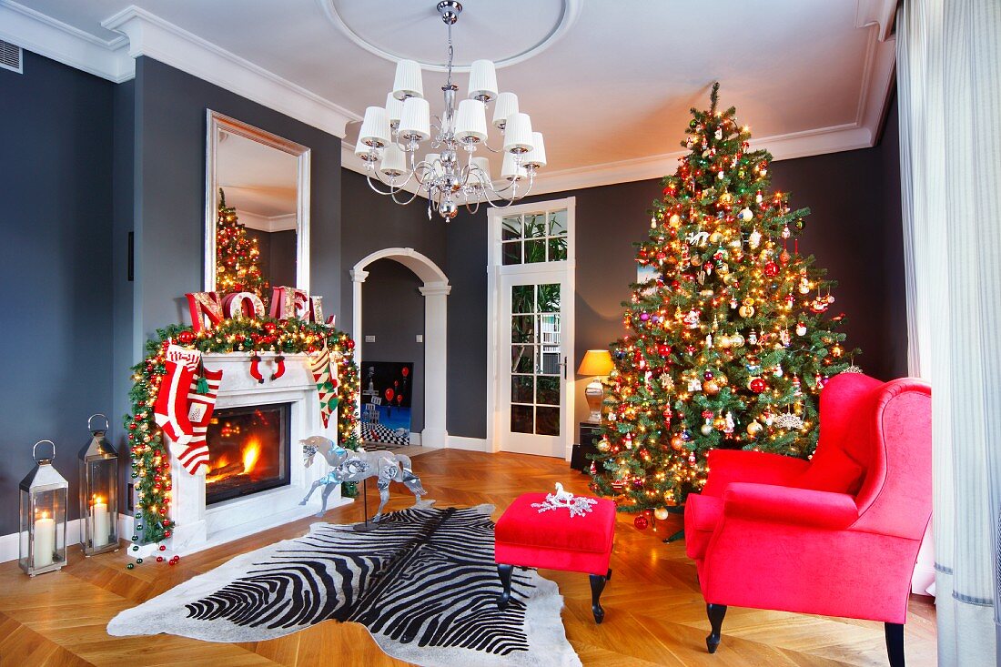 Red armchair and footstool and zebra-skin rug in front of decorated Christmas tree