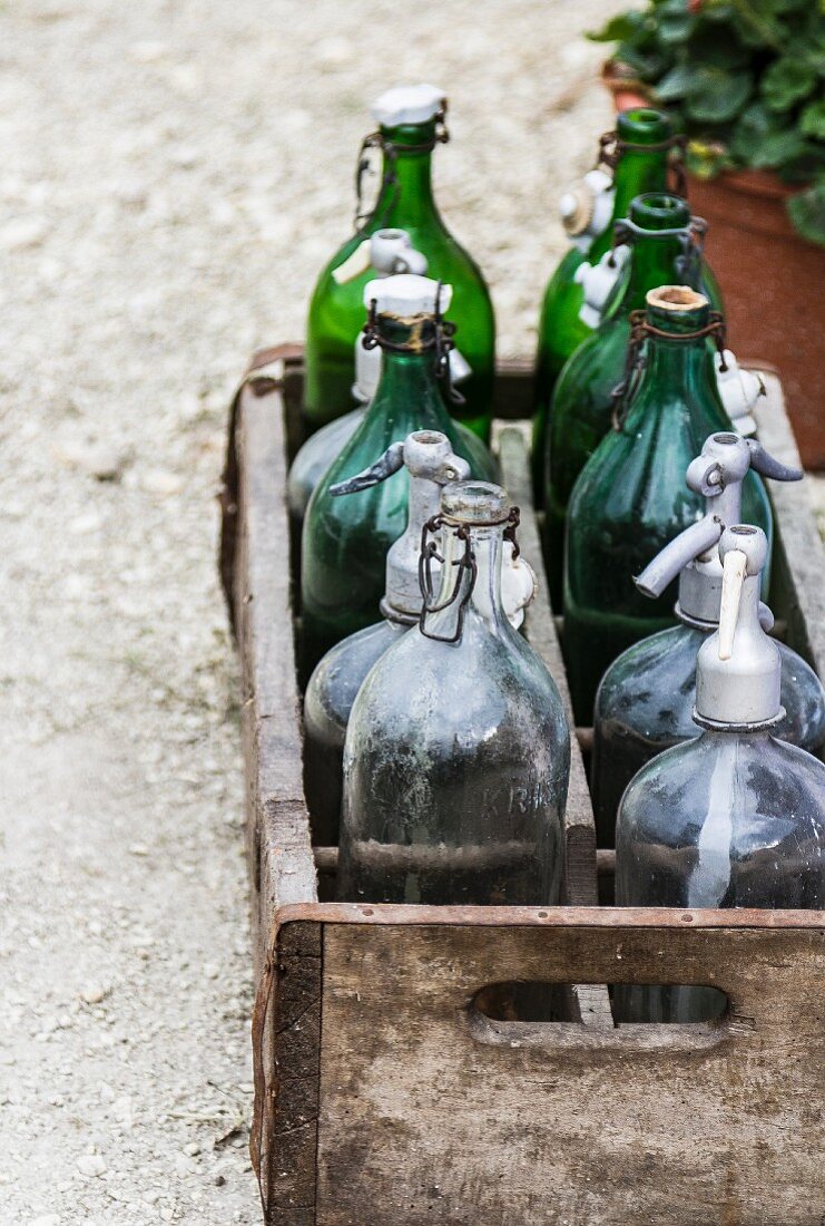 Holzkiste mit leeren Flaschen auf einem Gartenweg