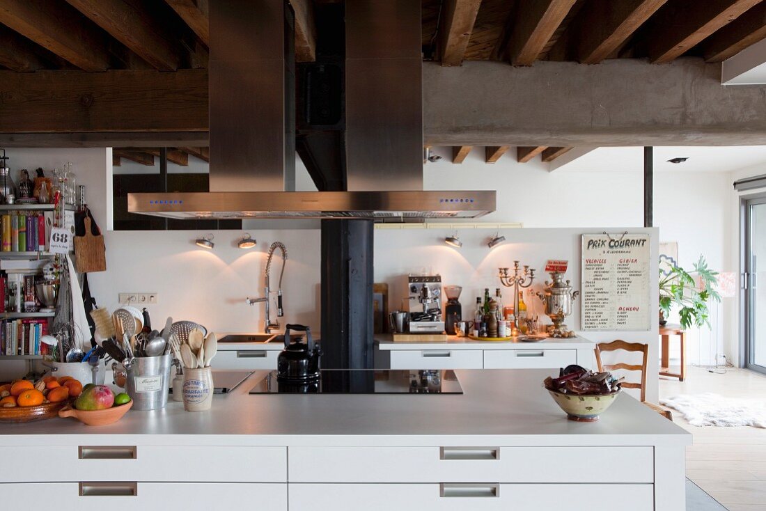 weiße Kücheninsel mit Schubladenschrank und Dunstabzug aus Edelstahl in Loft-Ambiente