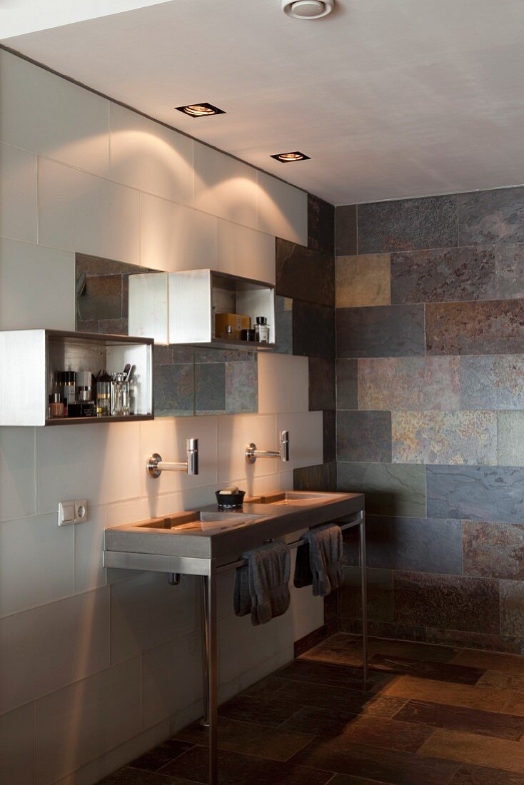 Modernes Bad mit minimalistischem Waschtisch auf Edelstahlgestell vor gefliester Wand und aufgehängte Regalboxen