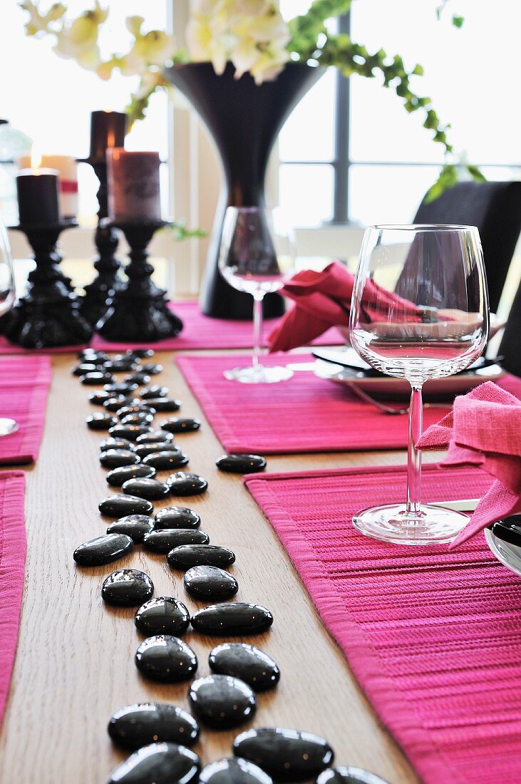 Table festively set with hot pink place mats and shiny black pebbles