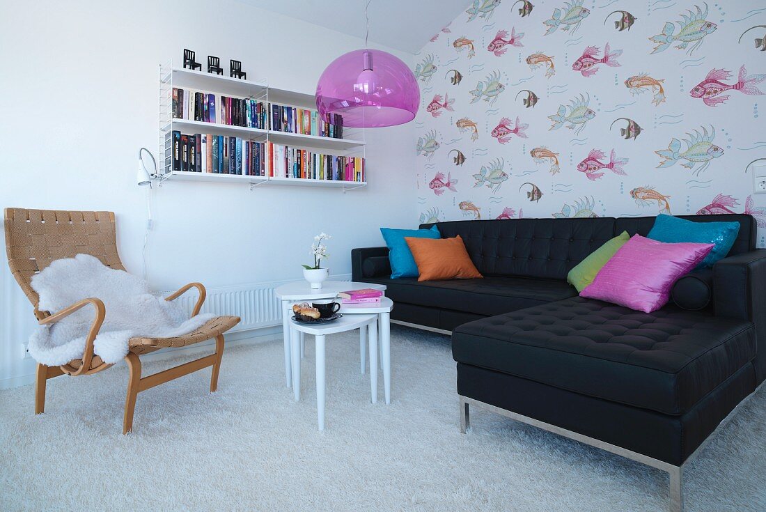 Sessel mit Tierfell und schwarze Sofakombination um weißem Couchtisch Set auf hellem Teppich, im Hintergrund tapezierte Wand mit Fischmotiven
