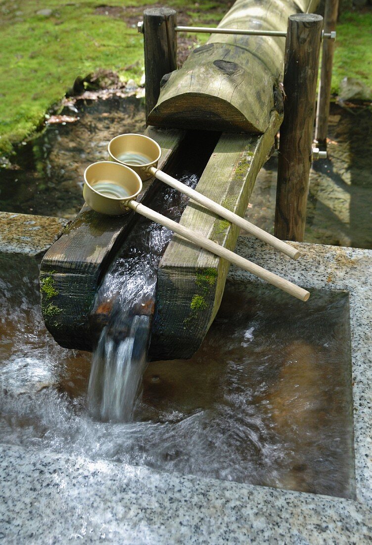 Quellwasser fliesst in das Steinbecken einer buddhistischen Tempelanlage; Japan