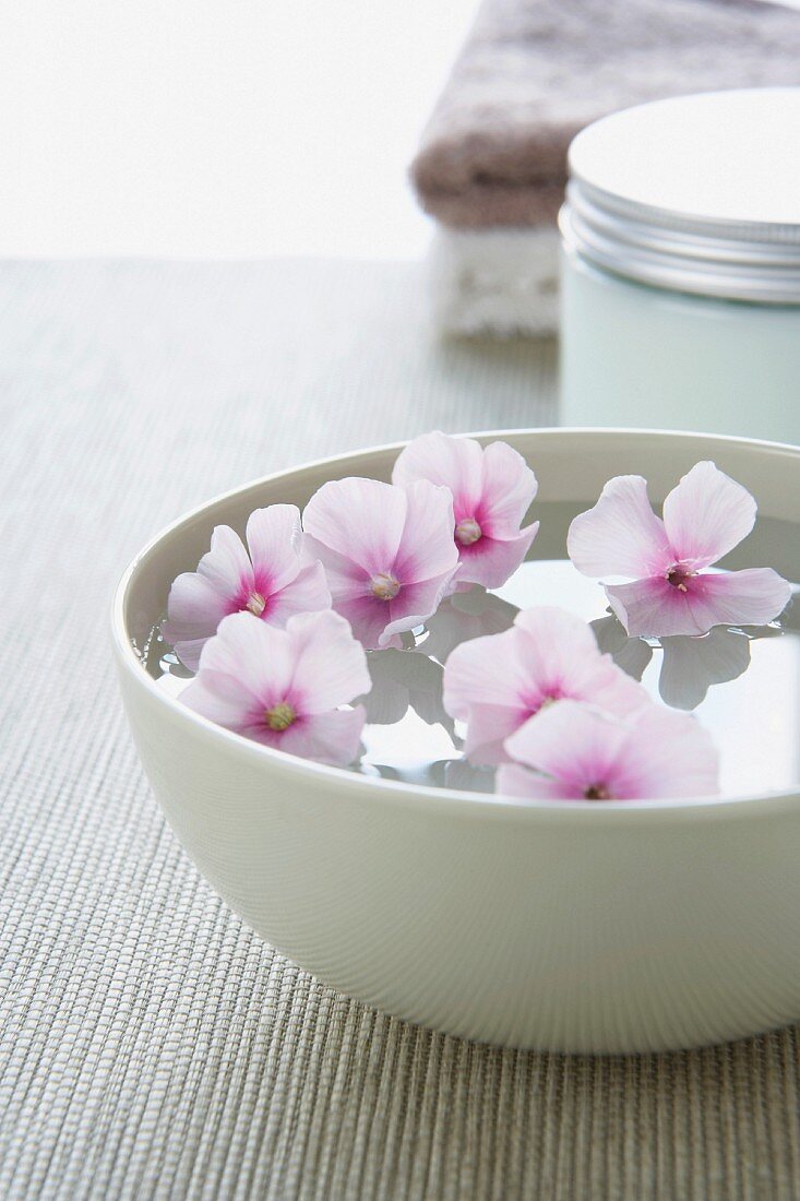 Flowers floating in white bowl of water