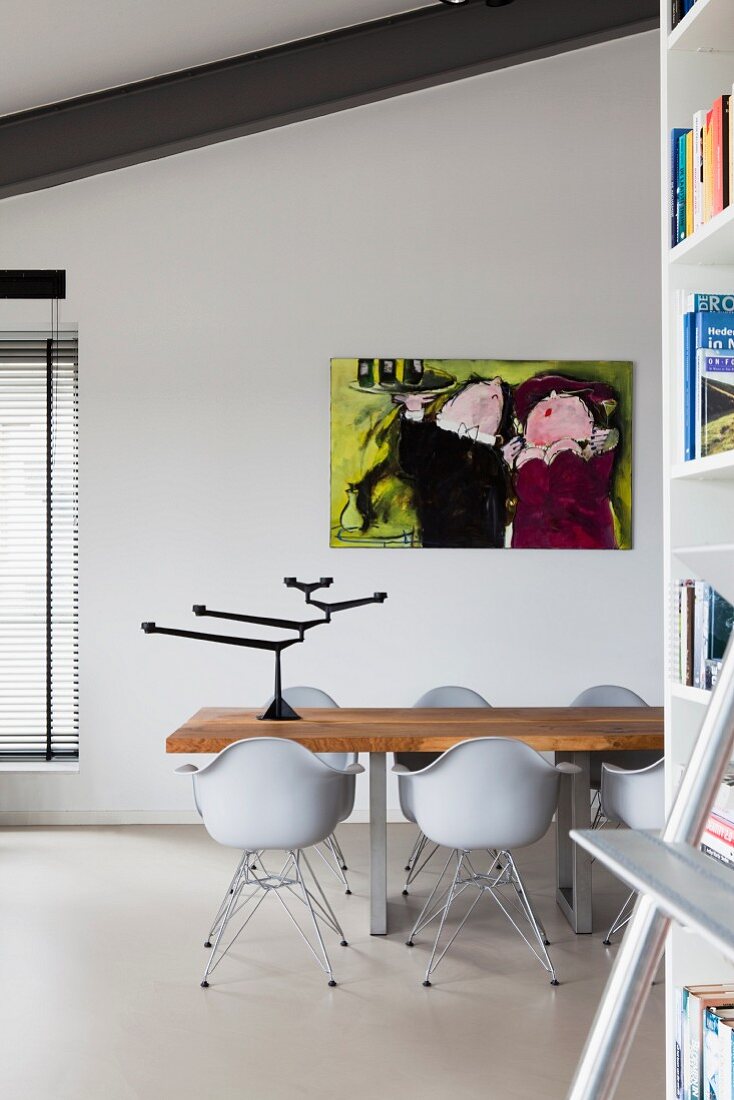 Esstisch mit Massivholzplatte und Klassiker Schalenstühle in Loft Wohnraum, an Wand modernes Bild