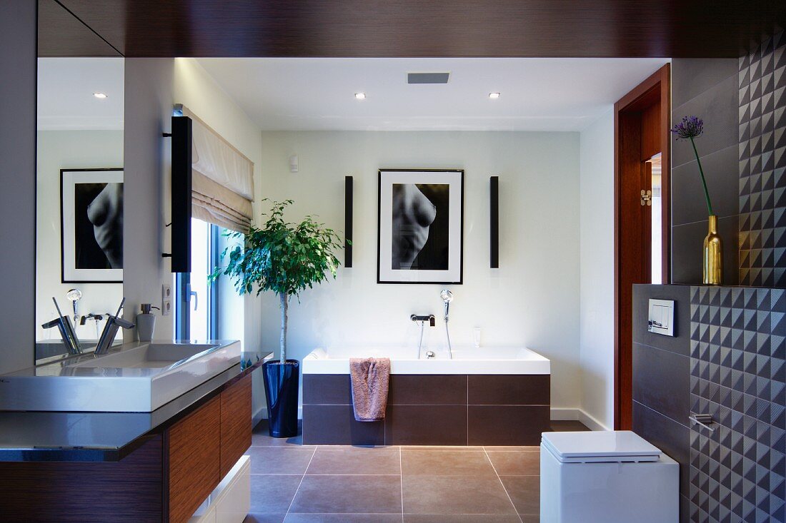 Elegantes Designerbad mit braunen Fliesen an Wand und Decke, seitlich Waschtisch, im Hintergrund Badewanne mit gefliester Front