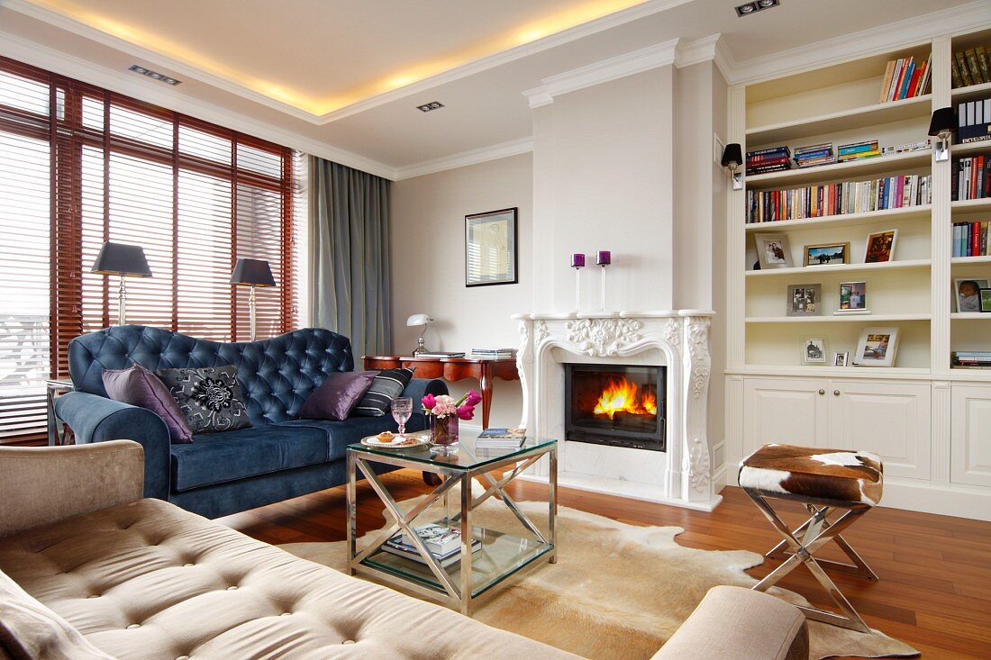 Beige and blue sofas around coffee table in traditional fireplace with fireplace and indirect ceiling lighting