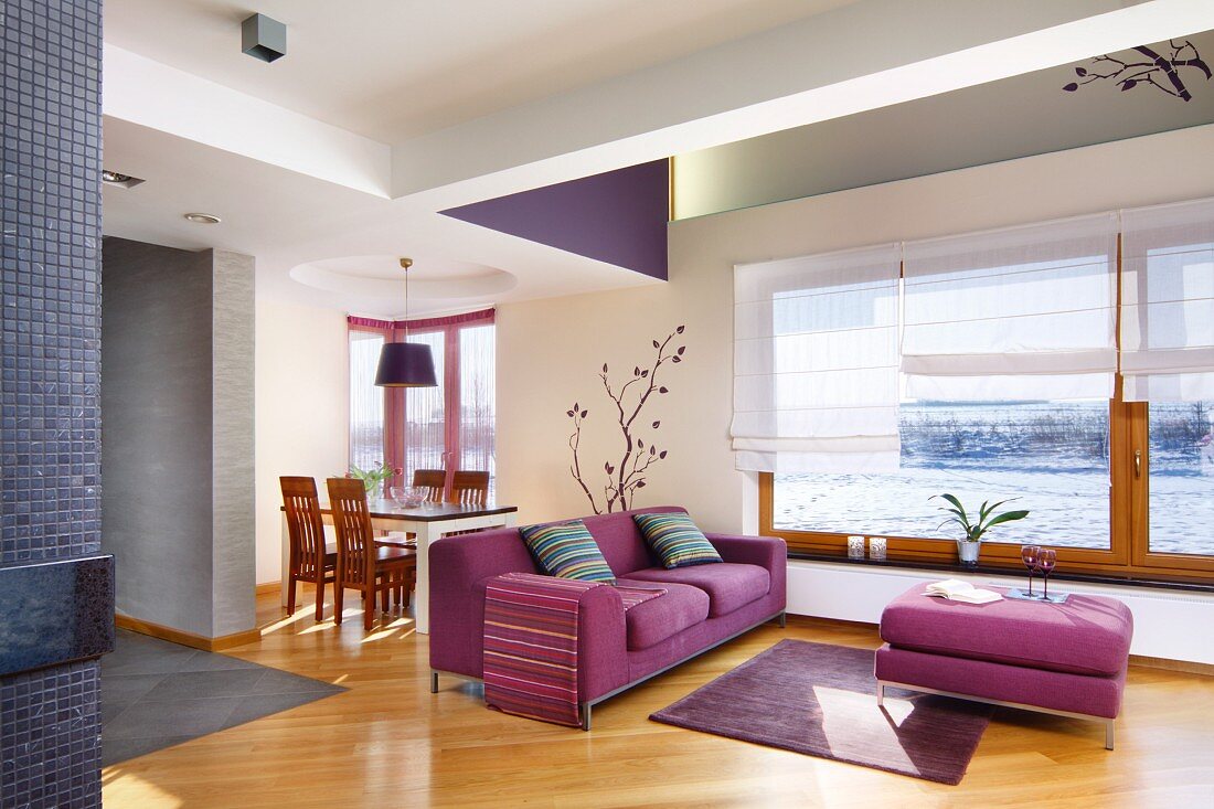 Pinkfarbenes Sofa mit passendem Couchtisch in offenem Wohnraum, im Hintergrund Essplatz, Parkettboden mit Diagonalverlegung