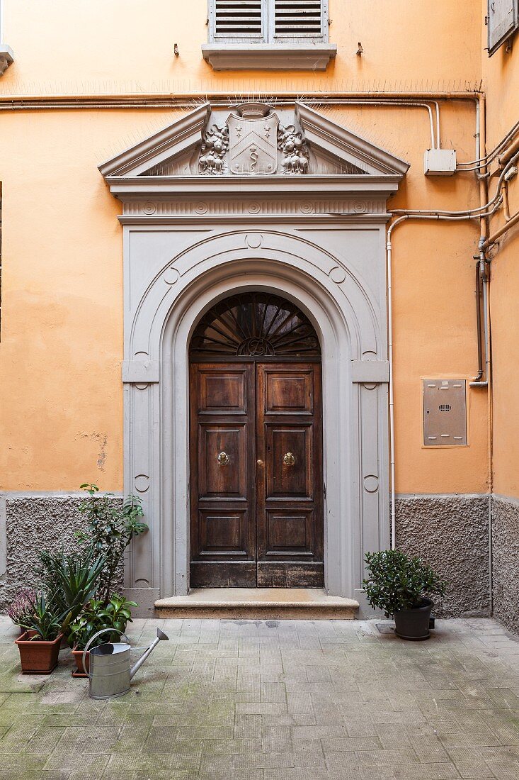 Traditioneller italienischer Palazzo-Eingang im Innenhof mit ockerfarbener Fassade und grauem Sockelbereich