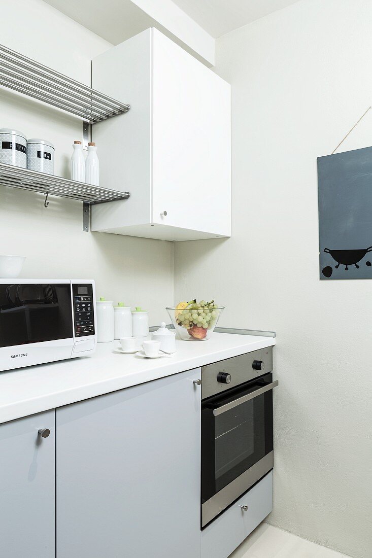 Hellgraue Küchenzeile mit weißem Hängeschrank und Metallregalen