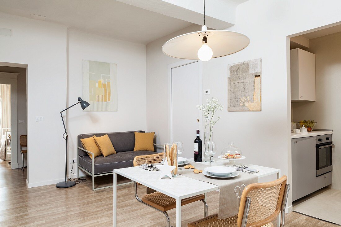 Small dining table, cantilever chairs and delicate, grey sofa in living area