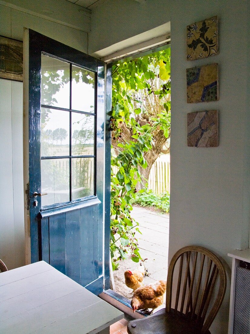 Küchentisch und Stuhl vor offener Haustür, blau gestrichen