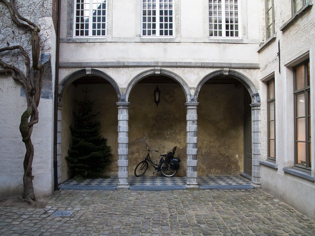 Gepflasterter Innenhof mit Blick auf Arkaden im Erdgeschoss eines traditionellen flämischen Stadthauses