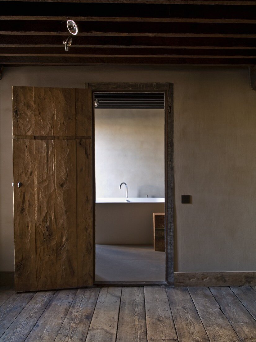 Offene Zimmertür in rustikalem Stil und Blick auf Badewanne