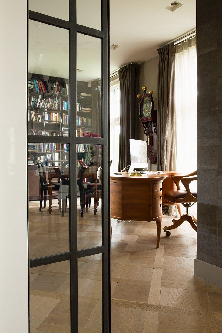 Stahltür mit Glaseinsatz, Blick auf Schreibtisch und Bücherwand