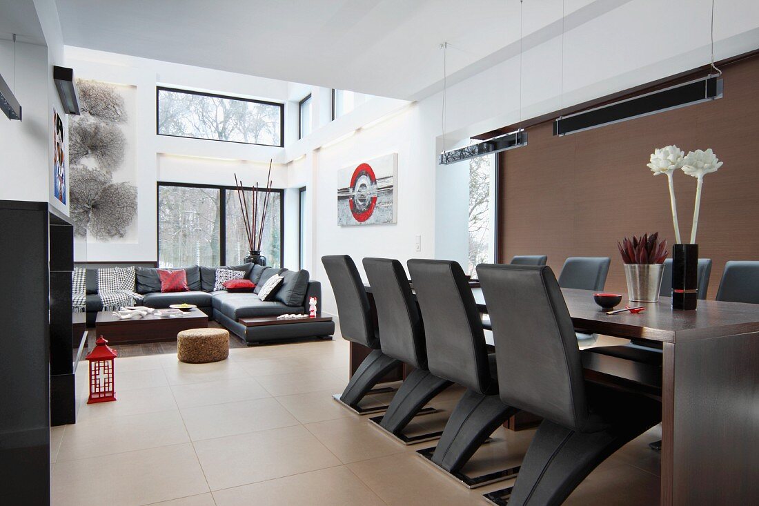 Futuristische Stühle an langer Essafel in offenem, zeitgenössischem Wohnraum; Loungebereich im Hintergrund