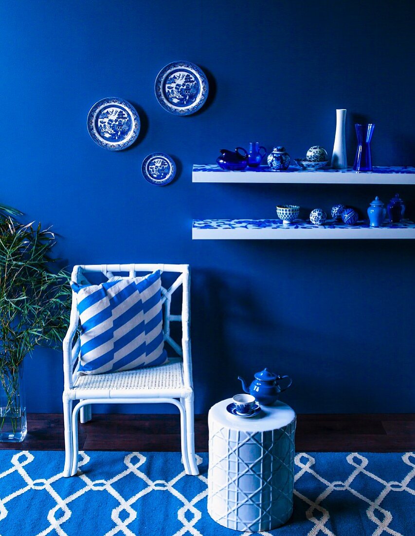 Blue and white arrangement of wicker chair, side table and vases on shelves
