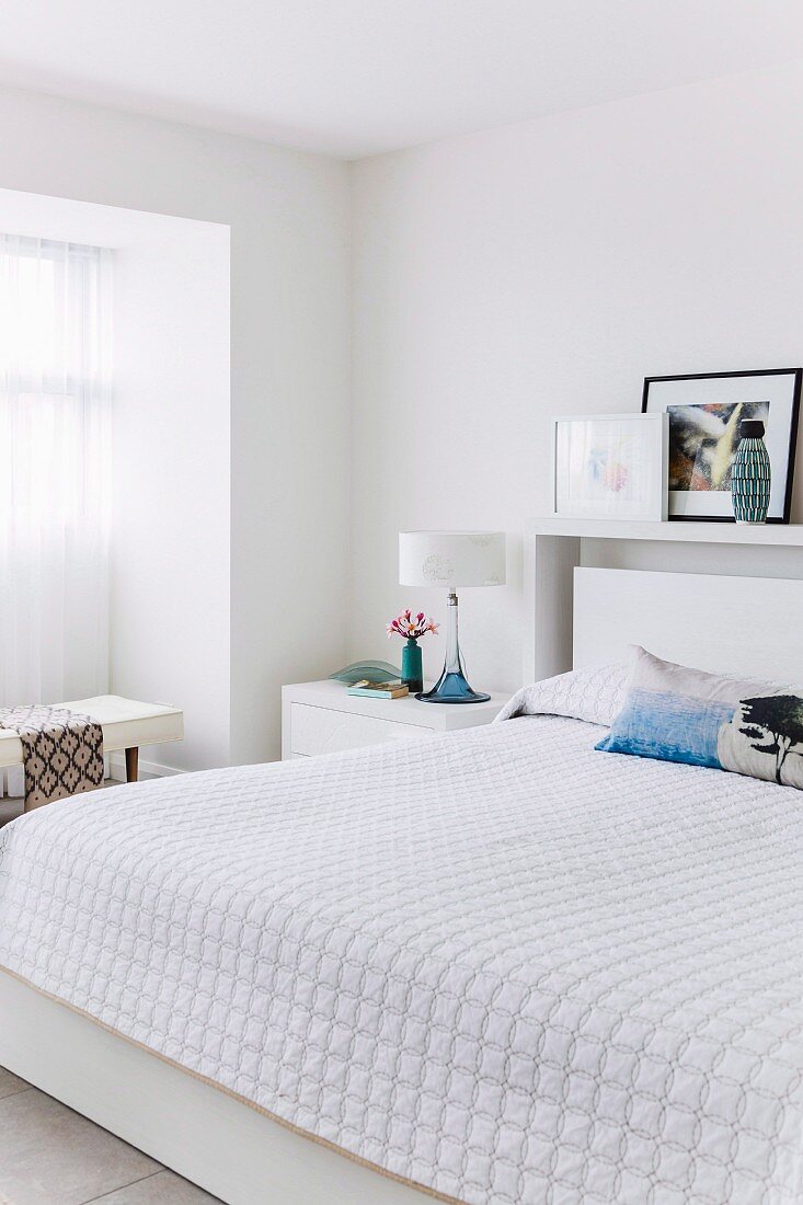 Double bed with white bedspread in modern bedroom