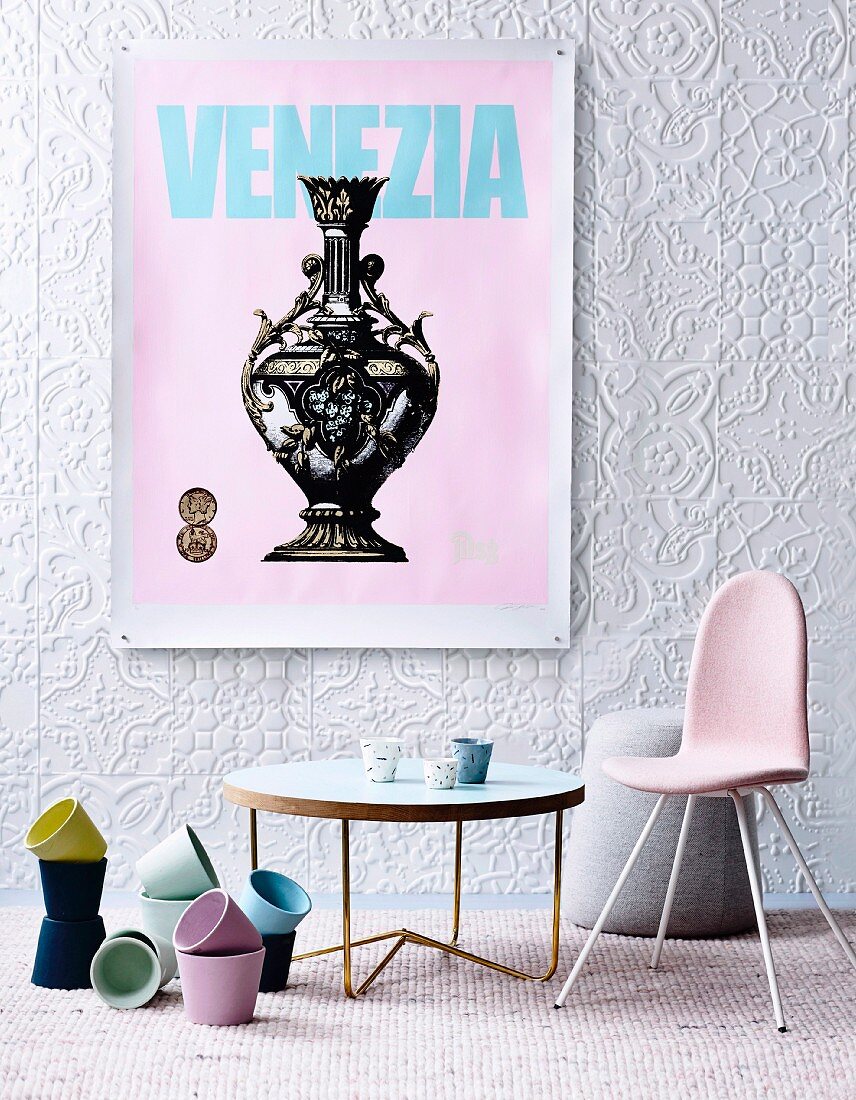 Pastel plant pots, coffee table and retro chairs below vintage poster on structured wallpaper
