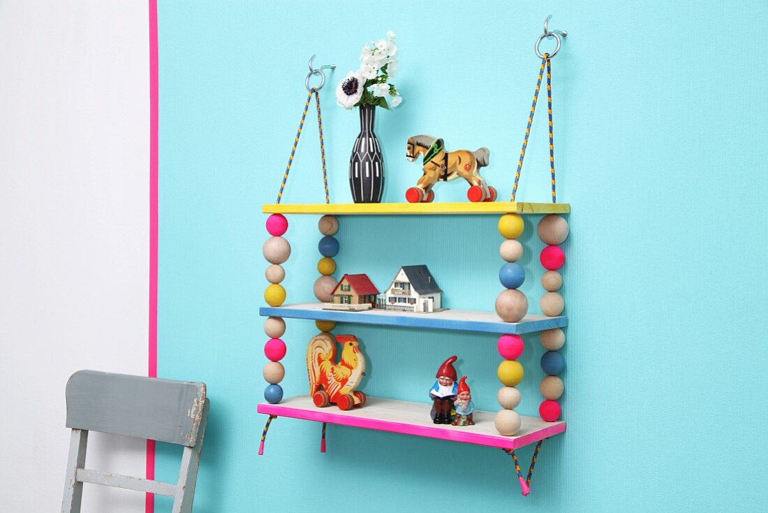 Colourful, hand-made shelves with wooden beads threaded on climbing ropes and hung from metal rings