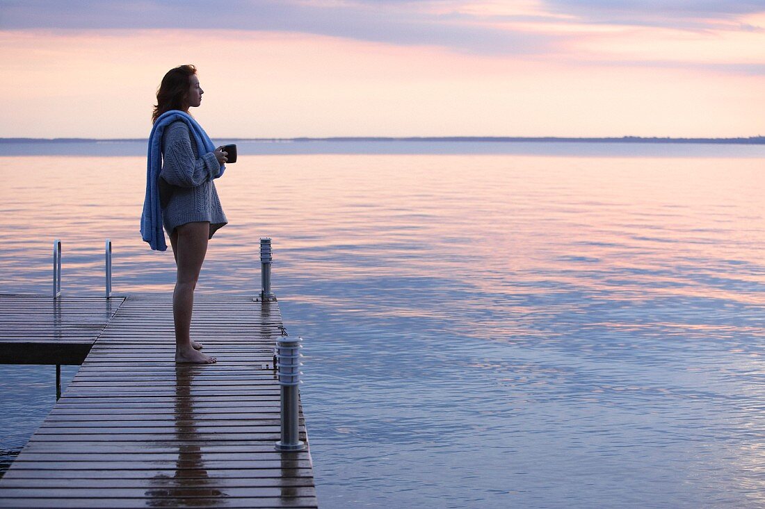 Woman looking out over water at dawn