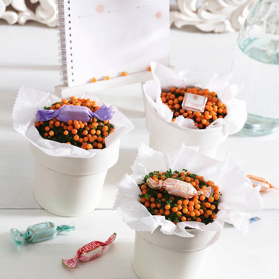 Small gifts or table decorations; potted coral bead plants wrapped in white tissue paper and decorated with wrapped sweets