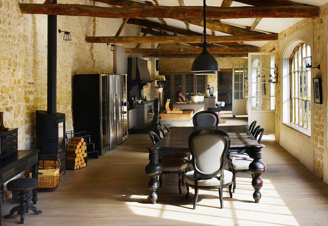 Partially renovated barn with rustic roof structure - Colonial-style dining set and kitchen area in open-plan interior