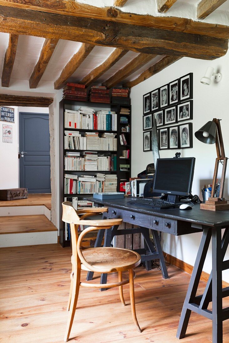Thonet Armlehnstuhl vor schwarzem Schreibtisch in rustikalem Ambiente mit Holzdecke