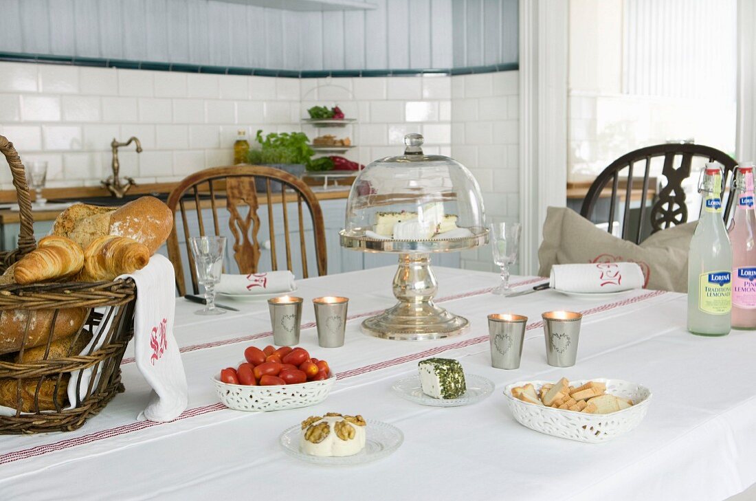 Mit Käse, Brot und Tomaten gedeckter Tisch in skandinavischer Landhausküche