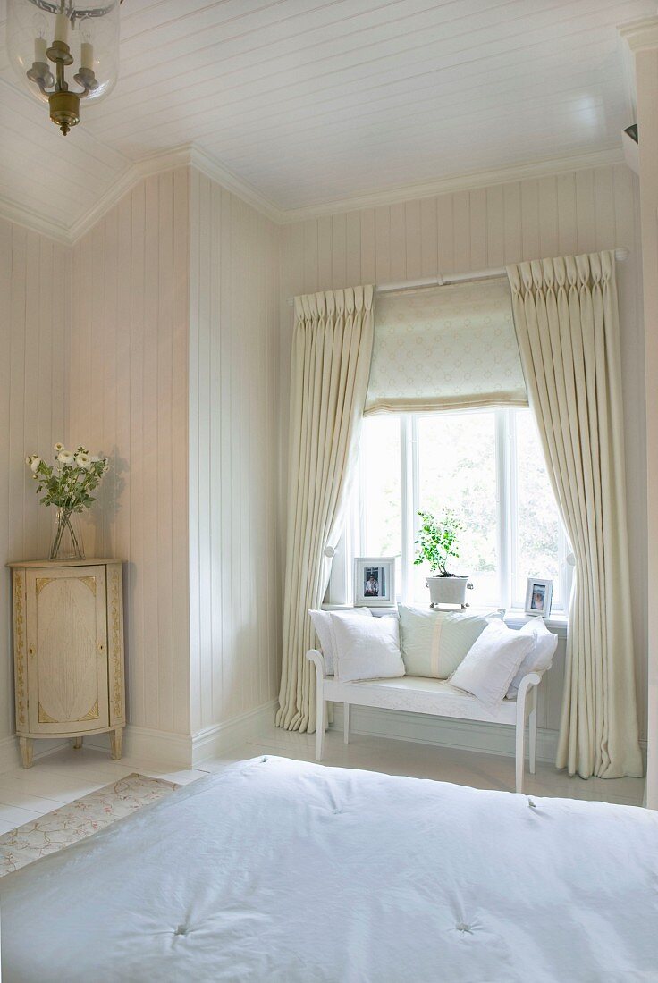 Elegant, country-house-style bedroom - view across double bed to delicate wooden bench below window