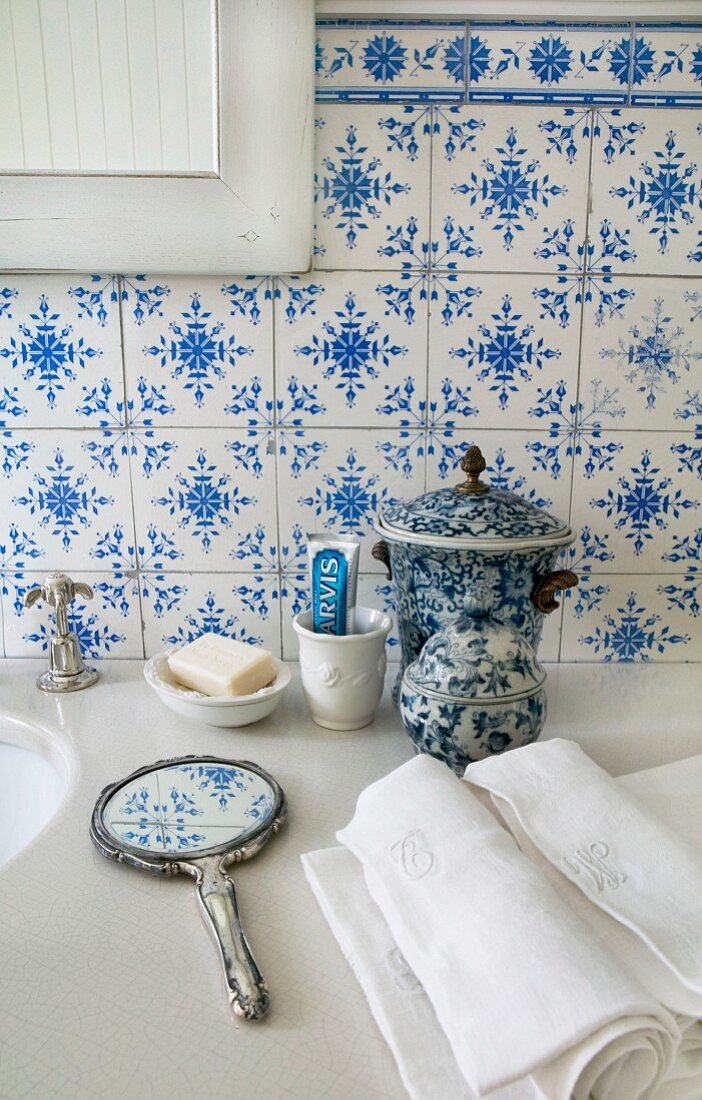 Traditionelle, blau-weiße Fliesen, Handspiegel und Keramik auf der Steinplatte eines Waschtischs