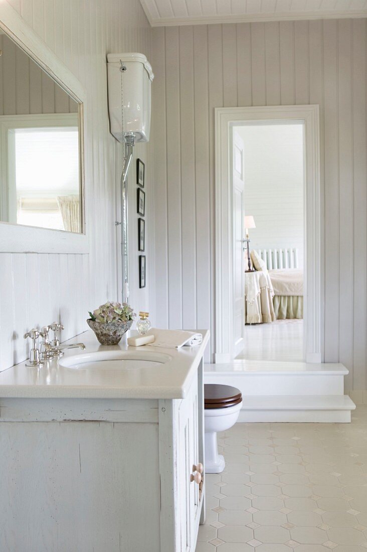 Washstand in Scandinavian, shabby-chic bathroom with view into adjoining bedroom
