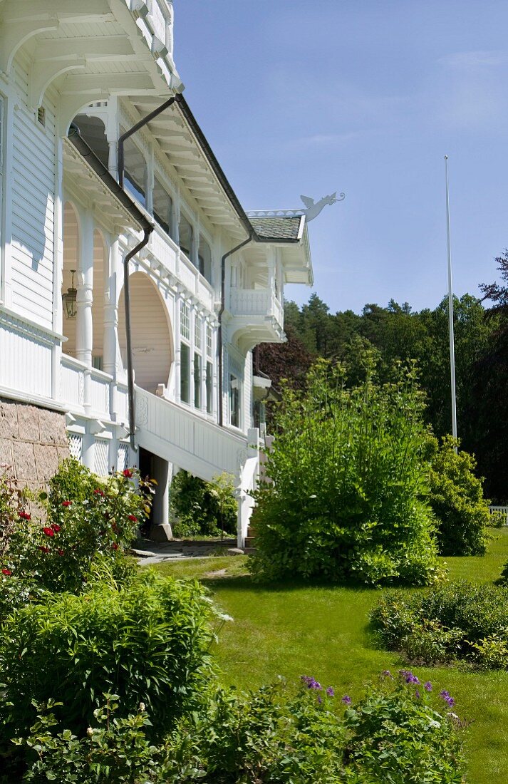 Garten in historischem Landsitz, Treppenabgang von der Terrasse des Herrenhauses mit weisser, Holzfassade