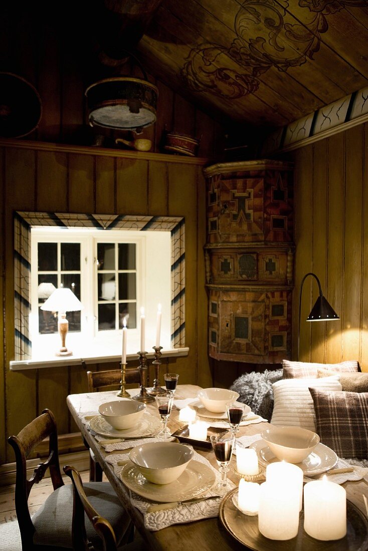 Gedeckter Tisch in beleuchtetem Esszimmer in einer rustikalen Holzhütte