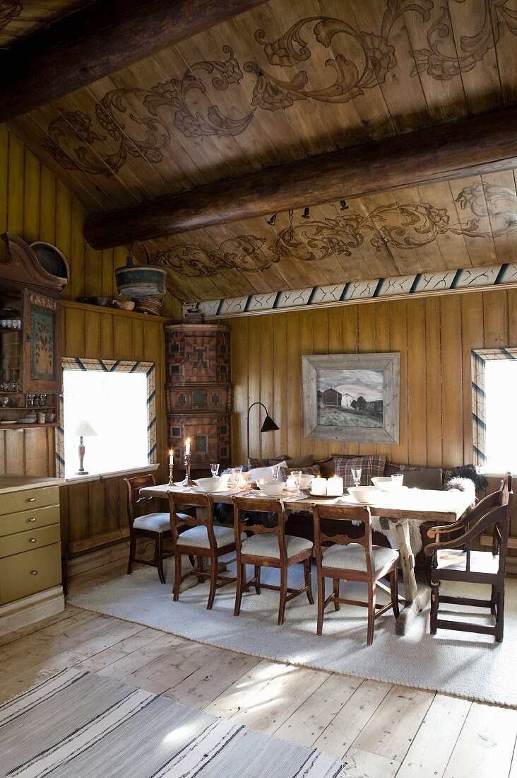 Esszimmer mit gedecktem Tisch und bemalter Holzdecke im alten Holzhaus