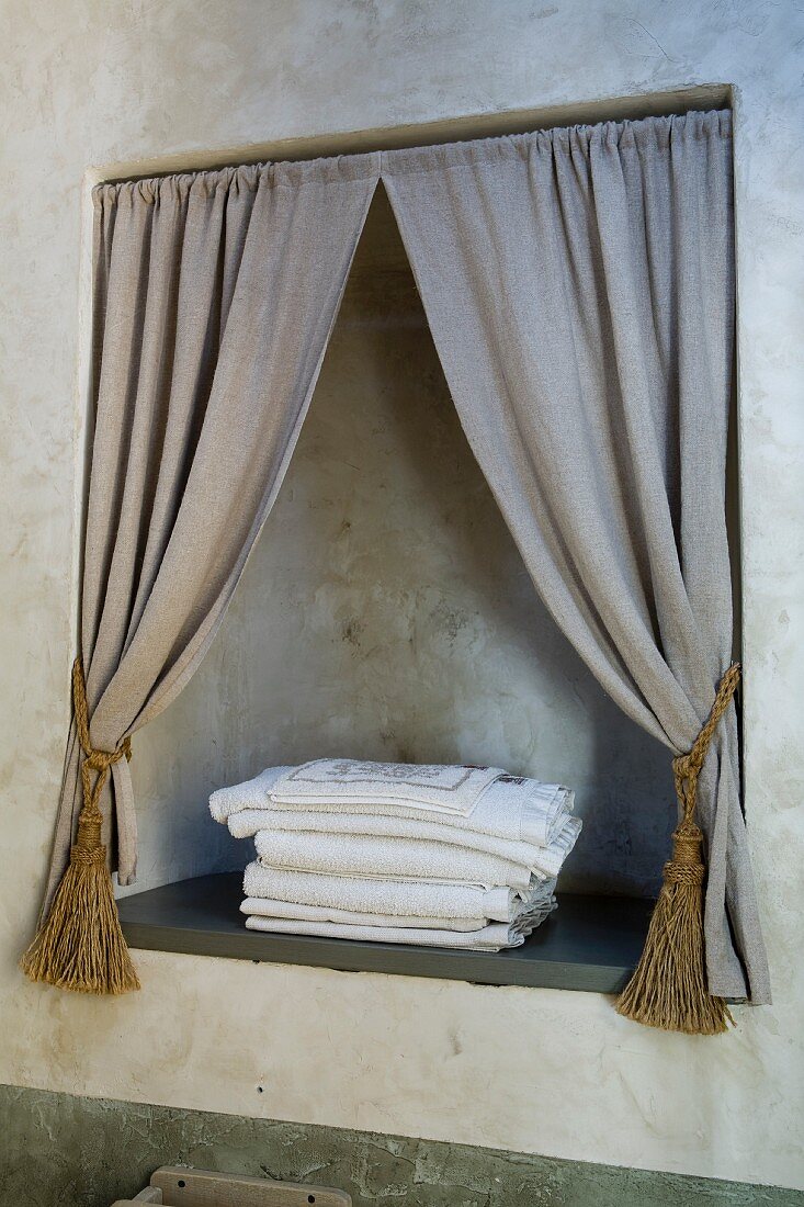 Niche with draped curtains in bathroom wall patinated with raw umber