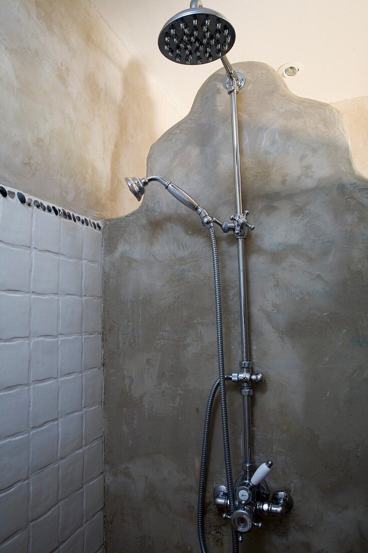 Retro Duscharmatur an einer patinierten, mit wasserabweisendem Harz verputzten Wand aus organisch geformten Wandelementen