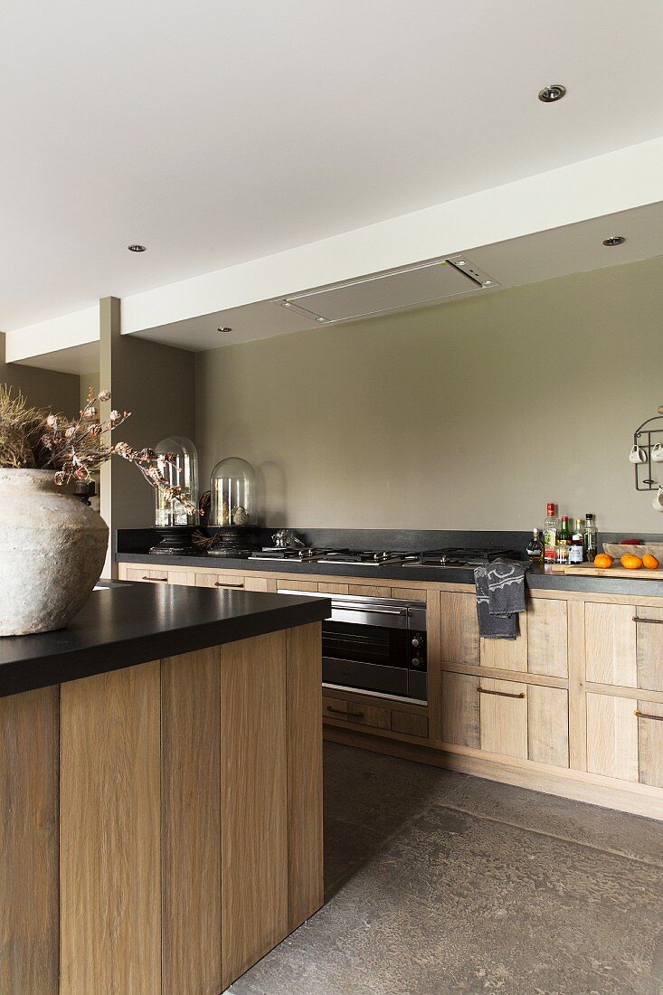 Kitchen island with black worksurface opposite counter in modern country-house style