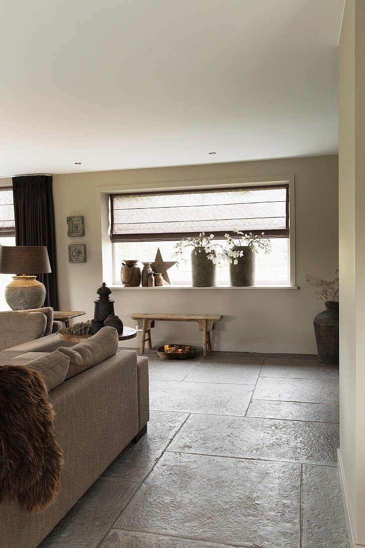 Open-plan interior with large stone floor tiles, sofas and Christmas decorations on windowsill