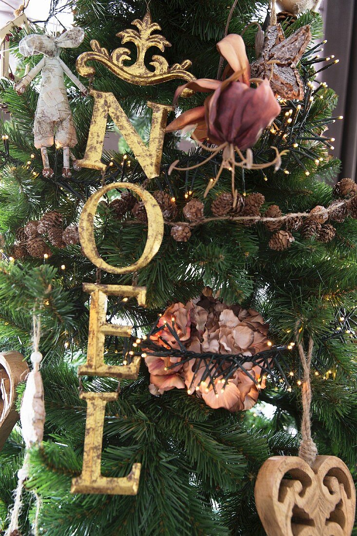 Christmas tree decorated with festive motto in gold letter ornaments